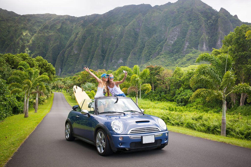 car road trip vacation young people taking selfie photo with phone during summer travel vacation. Tourists couple taking photos on Hawaii in convertible car, with smartphone camera