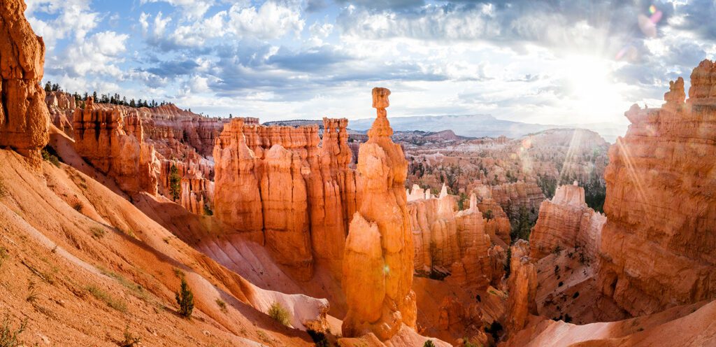 Panoramic view of scenic Bryce Canyon National Park with Thor's Hammer formation in golden morning light with sun peaking through the clouds during a beautiful sunrise in summer, Utah, western USA